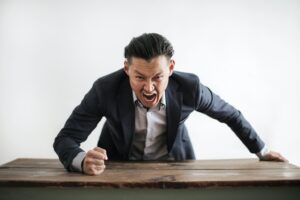 angry boss yelling and slamming fist on a desk